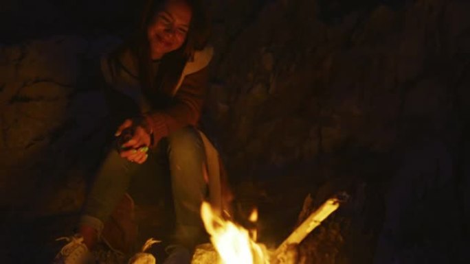 年轻女子坐在海岸篝火旁的肖像