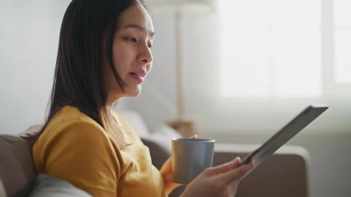 亚洲女性在家中使用数字平板电脑