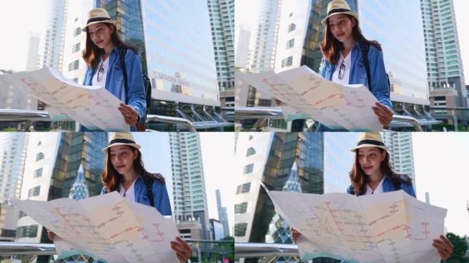 一位穿着旅游礼服的美丽亚洲妇女正在散布一幅以大城市为背景的地图。