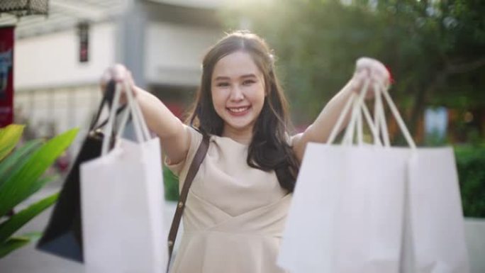 亚洲妇女向相机展示购物袋
