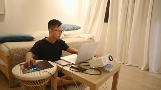 一名亚洲中国中年男子在家工作，在客厅安装了新的家庭办公室