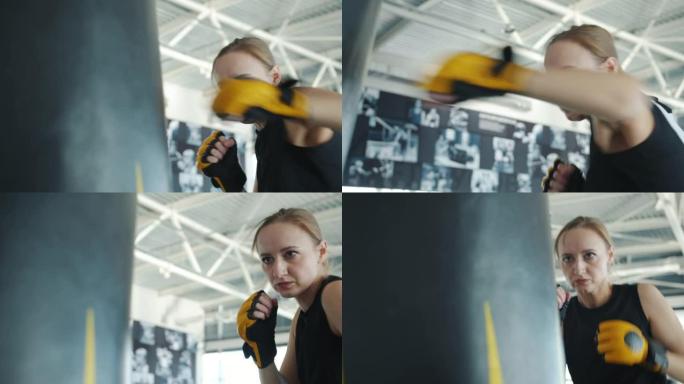 年轻女子拳击手套训练与沙袋在现代健身房