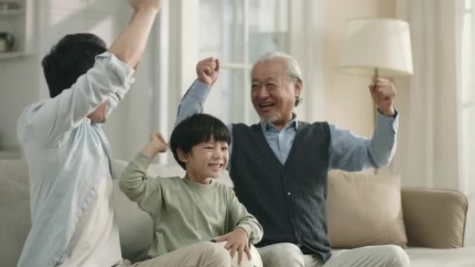 亚洲儿子父亲和祖父在电视上观看足球比赛直播