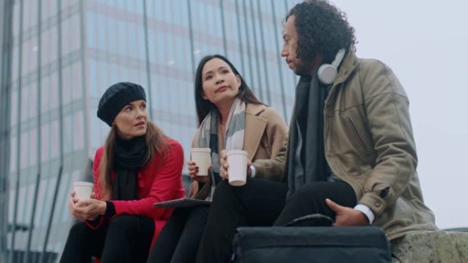 DS三个多种族的同事在外面喝咖啡休息时交谈
