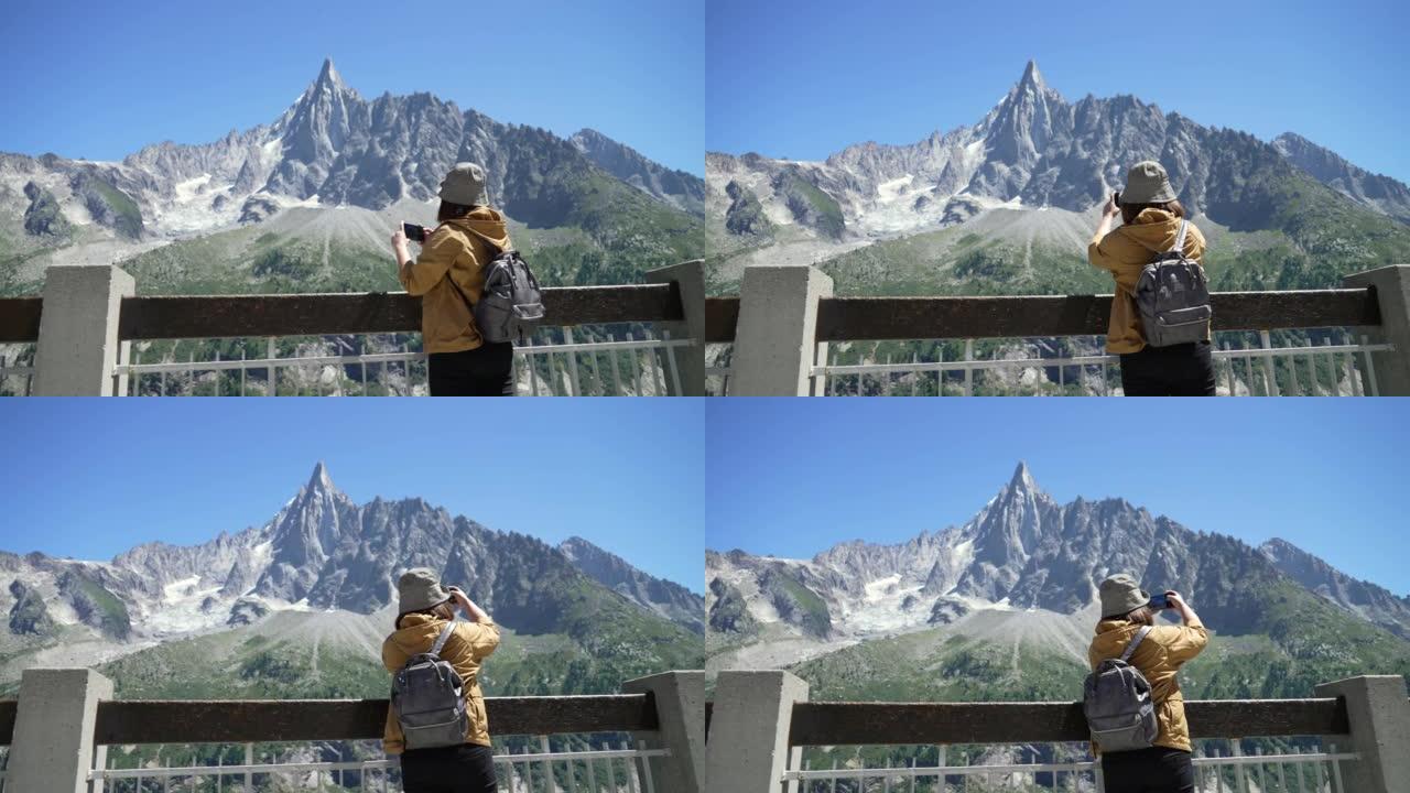 女旅行者在法国夏慕尼勃朗峰用智能手机拍照