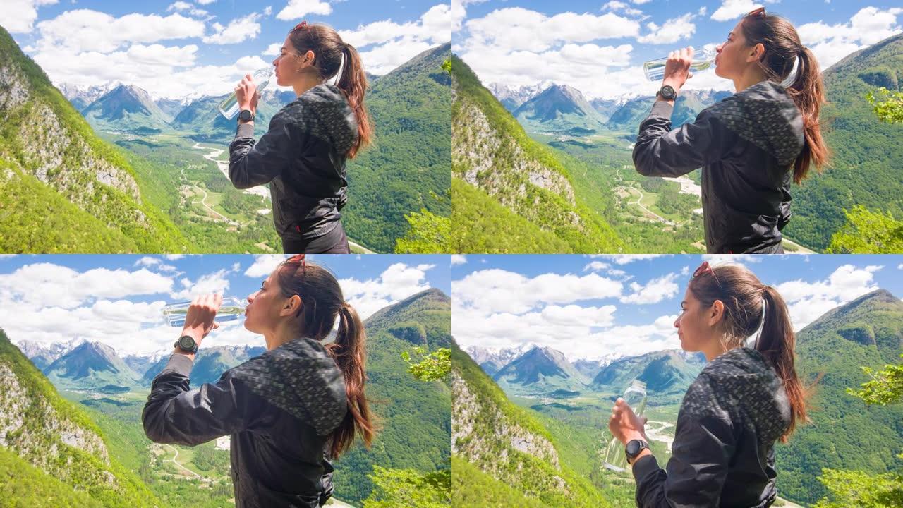 女徒步旅行者在美丽的晴天欣赏山景，喝水