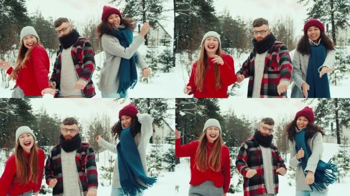 有趣的快乐宁静的多民族年轻朋友在美丽的白雪皑皑的冬季森林慢动作中穿着暖和的衣服一起跳舞。