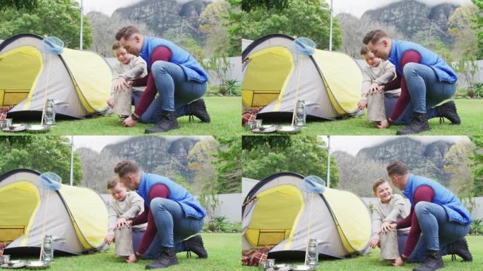 快乐的高加索父亲和儿子在花园里准备帐篷的营地