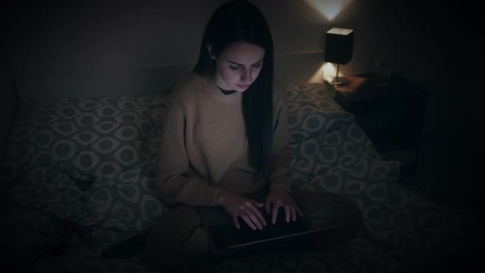 女人深夜在家床上使用笔记本电脑