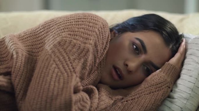4k视频片段，一名年轻女子躺在家里的沙发上看起来筋疲力尽