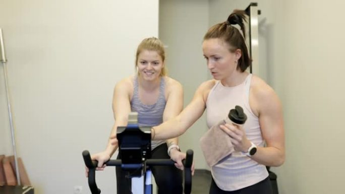 与私人教练一起在自行车机上锻炼的女人