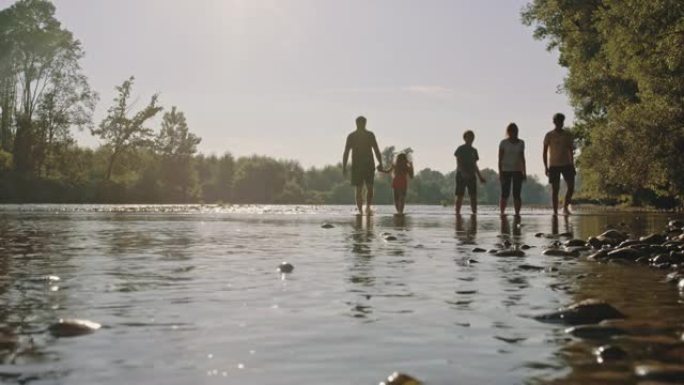 SLO MO一家带着三个孩子在河的浅水区散步
