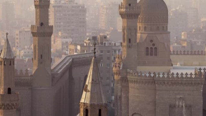 倾斜近距离拍摄苏丹哈桑清真寺和埃及开罗市。日落时轻雾中的清真寺和房屋