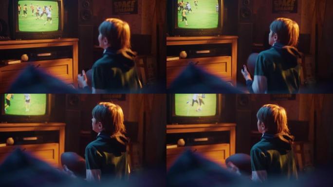 年轻的体育迷在家里通过电视观看美式足球比赛。帅哥支持他最喜欢的球队，兴奋地拿着足球。怀旧复古童年概念