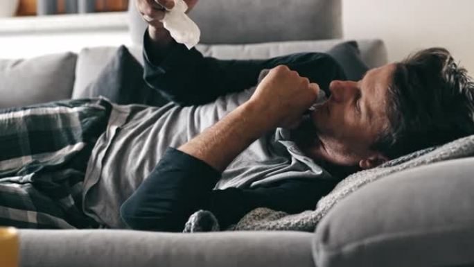 DS男子在家里的沙发上使用智能手机时遭受严重的咳嗽攻击