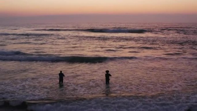两个男人在美丽僻静的海滩上冲浪钓鱼的鸟瞰图