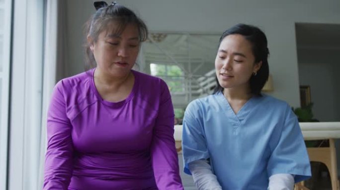 亚洲女性理疗师在手术中帮助女性患者用哑铃锻炼手臂