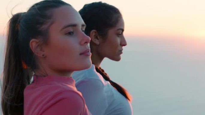 日落时坐在山顶上看海景的最好的朋友两个女人徒步旅行后休息，享受宁静的户外旅行冒险