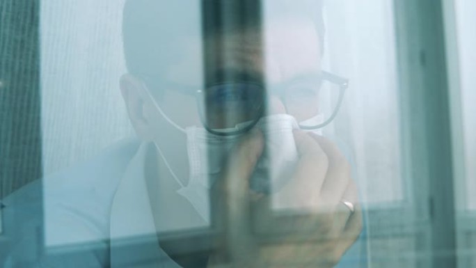 无聊的家伙在大流行期间呆在家里时透过窗户看。