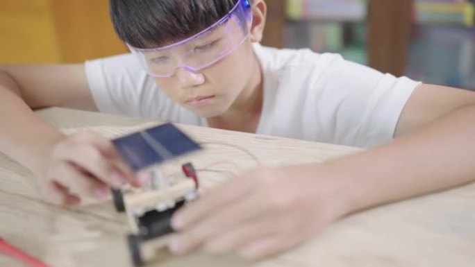 小学生专注于在学校实验室制作太阳能电池玩具车。