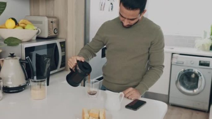 男人在厨房的餐桌上煮咖啡以获取能量，开始一天或早晨在他的家或公寓。咖啡师在家里将热浓缩咖啡倒入杯子中