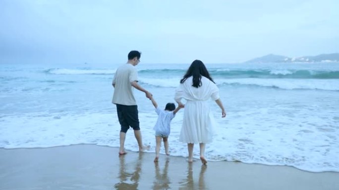 亚洲父母子在海边散步出海