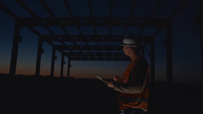 SLO MO建筑承包商在黄昏时在建筑工地使用数字平板电脑