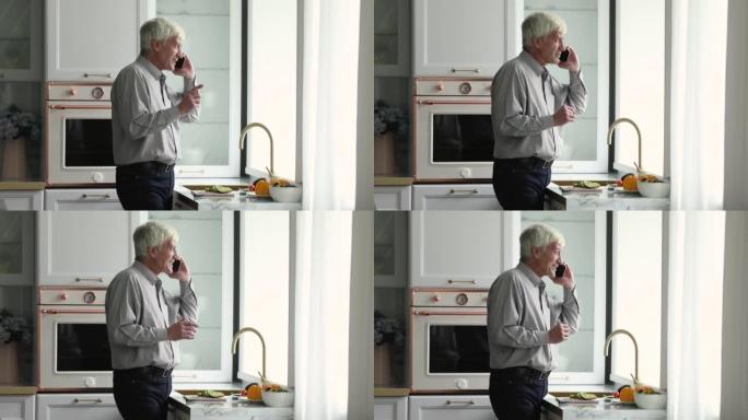 站在厨房里的老人在智能手机上讲话
