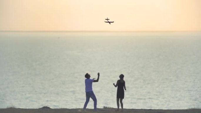 男人和女人在海滩上扔玩具飞机。慢动作