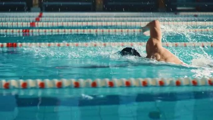 成功的男子游泳运动员赛车，在游泳池游泳。职业运动员决心使用前爬行自由泳赢得冠军。彩色电影镜头。侧视图