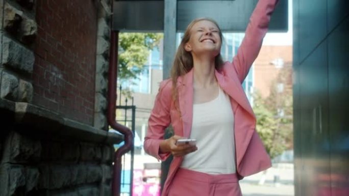 嬉戏的年轻女子在夏日使用智能手机在城市街头跳舞