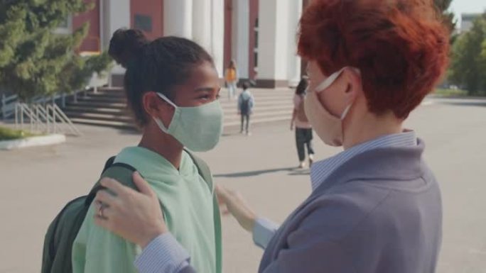 有爱心的女人给女学生戴上口罩