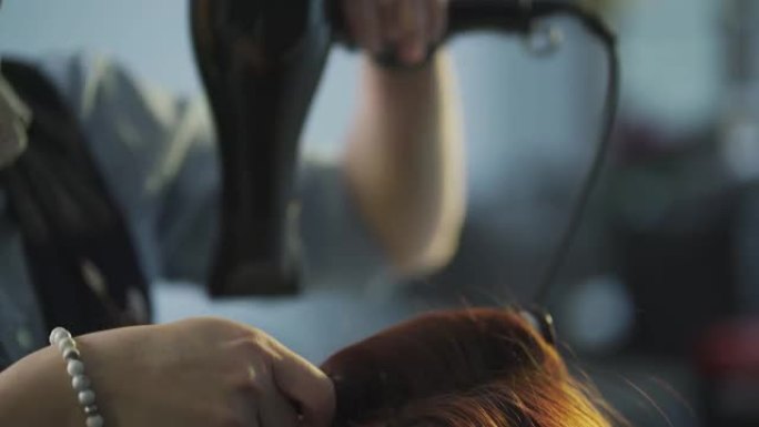 亚洲中国女性发型师在发廊为她的顾客吹梳湿长发