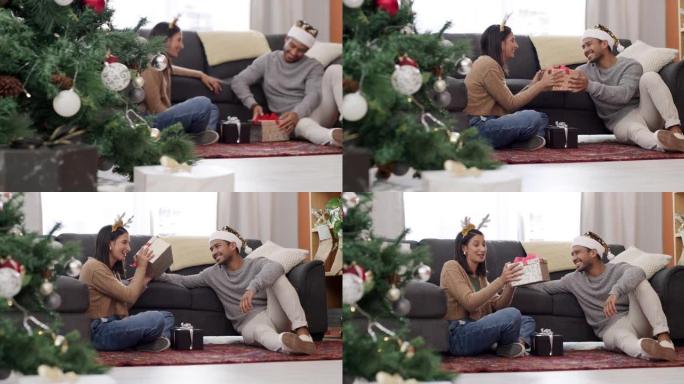 一对年轻夫妇坐在休息室地板上在家一起交换圣诞礼物的4k视频片段