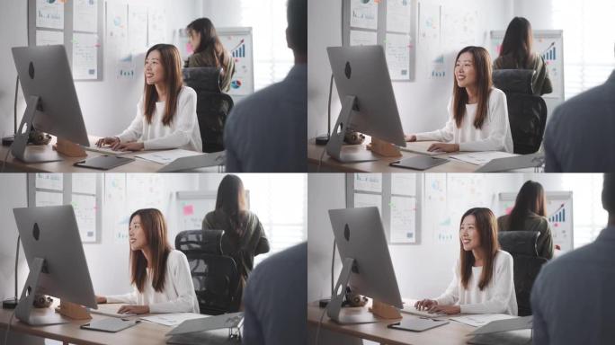 亚洲女商人与同事一起在计算机上工作