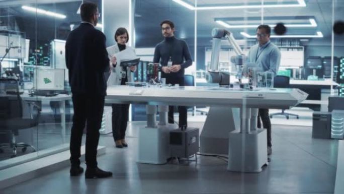 不同的工业机器人工程师团队聚集在一张有机械臂的桌子周围。科学家使用笔记本电脑来操纵和编程机器人，以拾