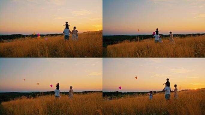 SLO MO家族在日落时分在草地中央向空中释放气球