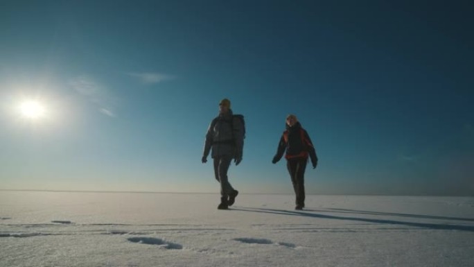 背着背包的男人和女人走过白雪皑皑的田野。慢动作