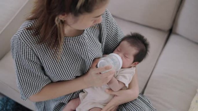年轻的母亲在怀里给她的新生婴儿喂奶。