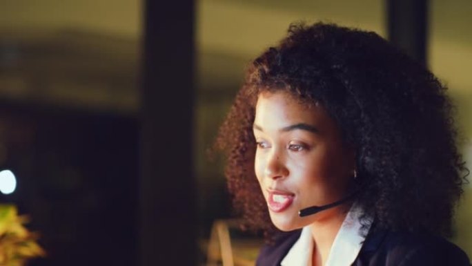 年轻的女性呼叫中心代理在办公室工作到很晚时与客户进行咨询。一位黑人女性服务台工作人员与客户交谈并在黑
