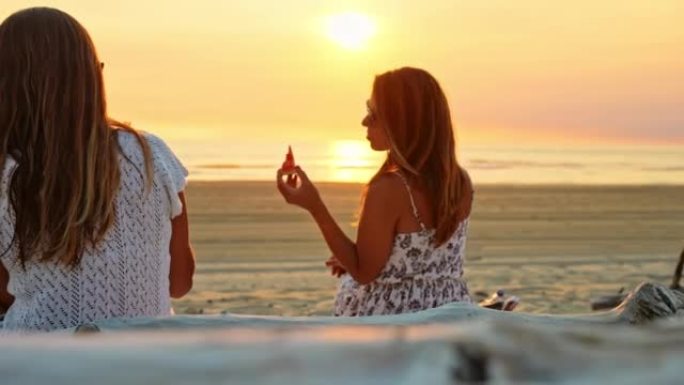 WS两名妇女在日落时在海滩上吃西瓜时说话