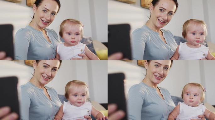 高加索母亲在家中与婴儿在智能手机上自拍
