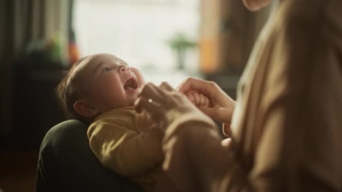一个可爱的亚洲婴儿在母亲的腿上休息的肖像，当她对她说话时。活跃的小孩咕咕叫，试图交流，用充满爱和感情
