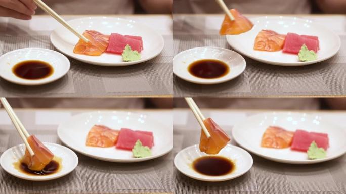 4K UHD慢动作手持: 鲑鱼生鱼片蘸酱油碗用筷子。日本美食美食，亚洲文化。健康食品概念。