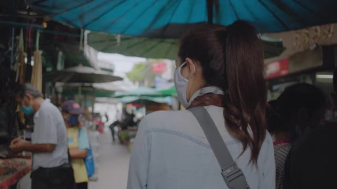 亚洲成年妇女在当地旅游场所散步和购物。迷人的女性在当地旅行时寻找街头美食。单人旅行者概念。