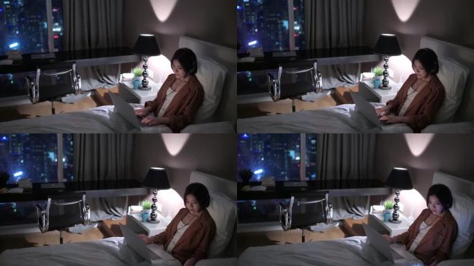 亚洲中国美女晚上在卧室用笔记本电脑工作