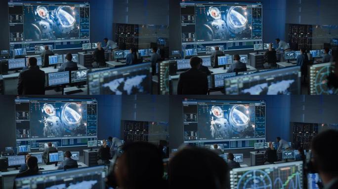 任务控制中心的一群人在大屏幕上与空间站上的宇航员建立了成功的视频连接。飞行控制科学家坐在电脑前。