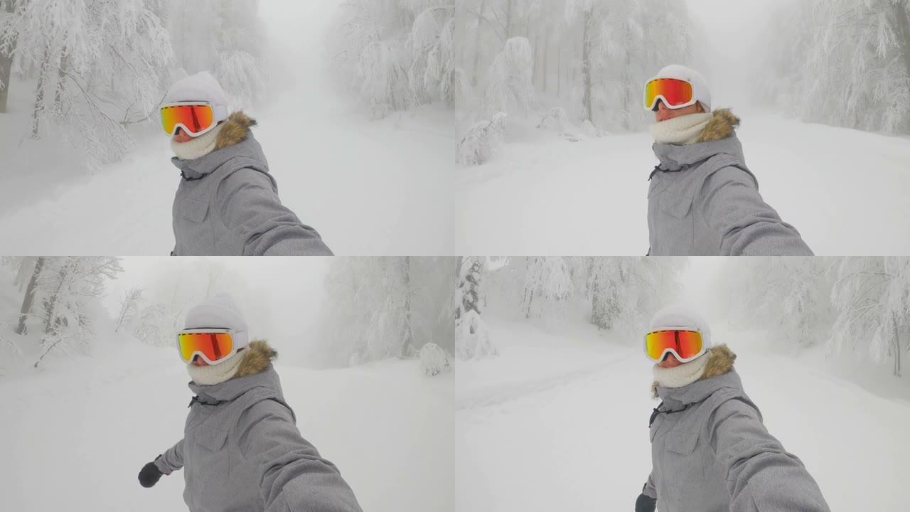 自拍照: 戴着橙色护目镜的女性滑雪者沿着滑雪胜地的斜坡骑行。