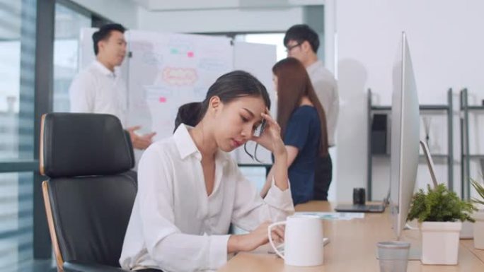 女商人在小型现代办公室会议室的计算机桌面上解决项目研究问题。亚洲人职业倦怠综合症的概念。