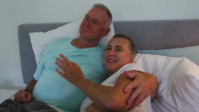 高加索高级夫妇在家里的床上互相拥抱